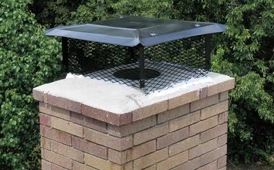 Stock photo- chimney cap-Black Velvet Chimney Black chimney with custom cap on brick chimney and greenery in the background