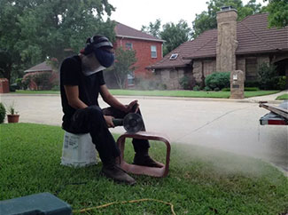 Stock photo working on flue-Black Velvet Chimney Technician sitting on ground working on flue with safety equipment on