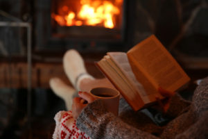 Woman resting with cup by fireplace