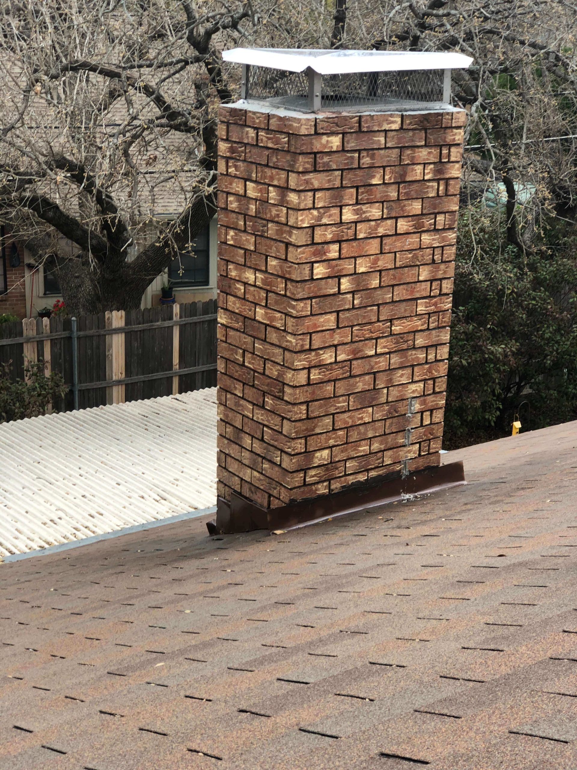 Multi-colored brick chimney with chimney cap on roof-leaky chimney repair